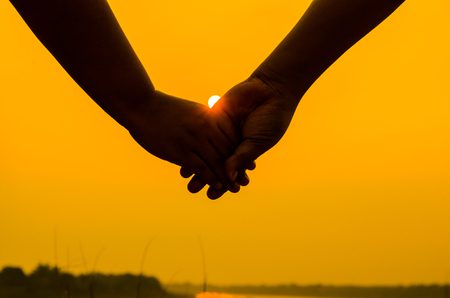63583099 pareja romantica con las manos entrelazadas a contraluz por un sol brillante de la tarde en una