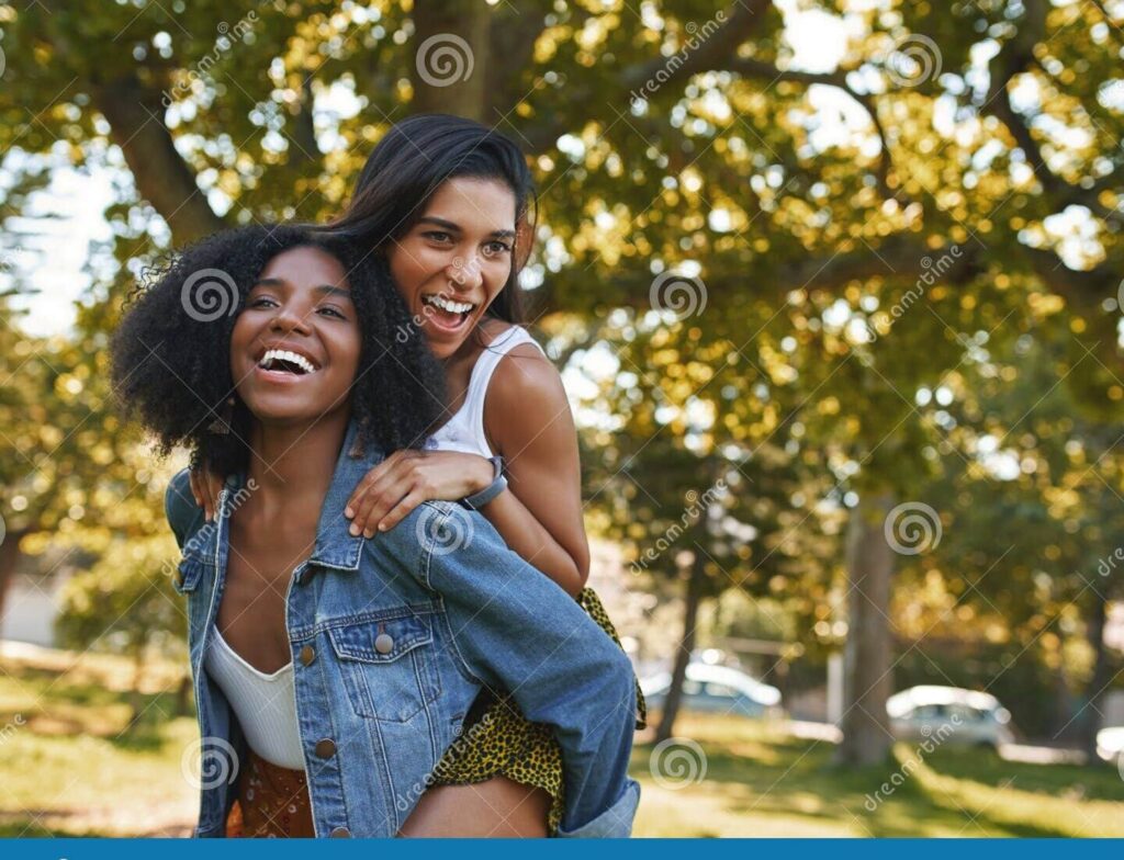 dos amigas riendo y abrazandose en un parque