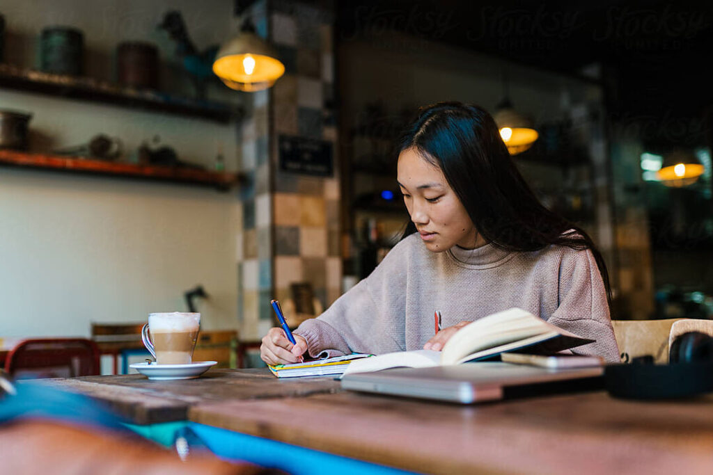 un estudiante tomando notas en un cafe mientras estudia