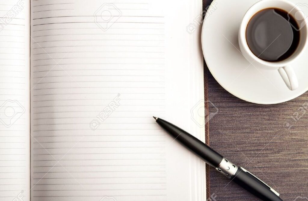 una imagen de un escritorio con una pluma un cuaderno y una taza de cafe