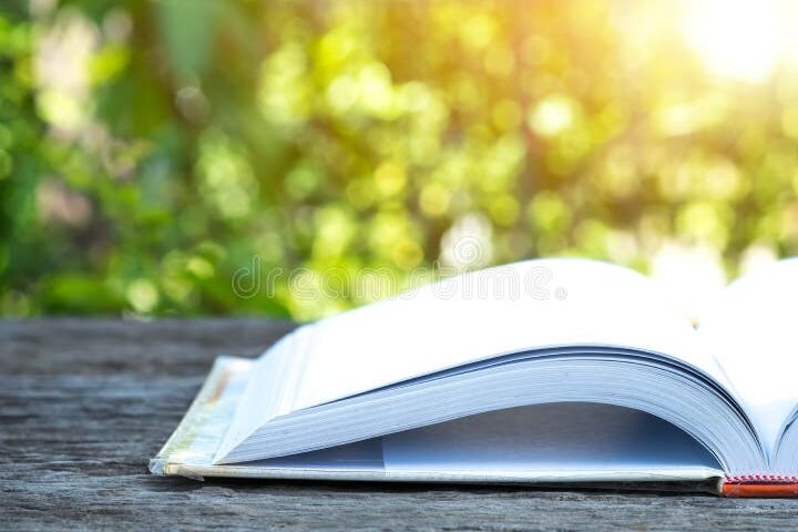 una imagen de un libro abierto con una pluma y una hoja de papel a un lado
