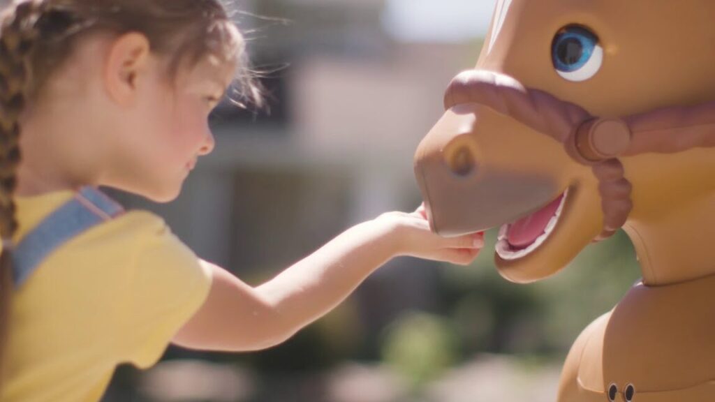 una imagen de un nino sonriente montando un caballo de juguete grande