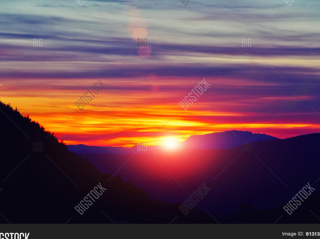 una imagen de un sol naciente sobre un paisaje montanoso
