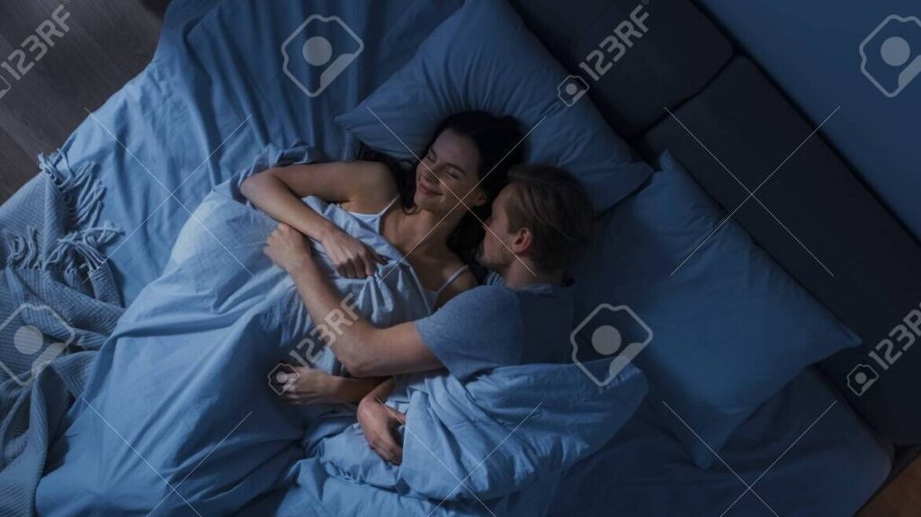 una imagen de una pareja abrazada en la cama mirandose tiernamente mientras duermen