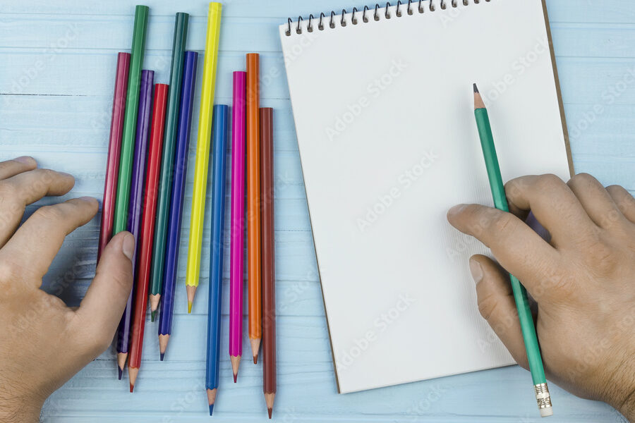 una imagen de una persona dibujando en un cuaderno con lapices de colores