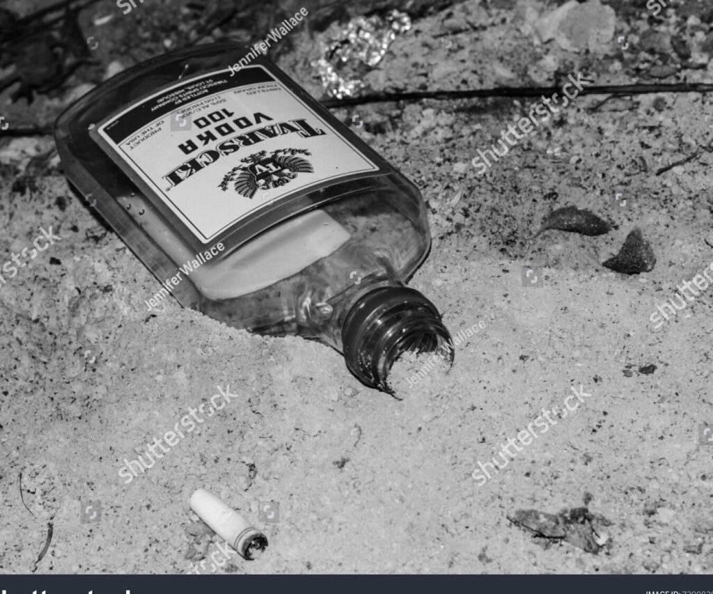 una imagen en blanco y negro de una botella de alcohol rota en el suelo