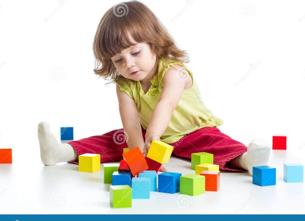 una nina pequena sonriendo mientras juega con bloques de construccion