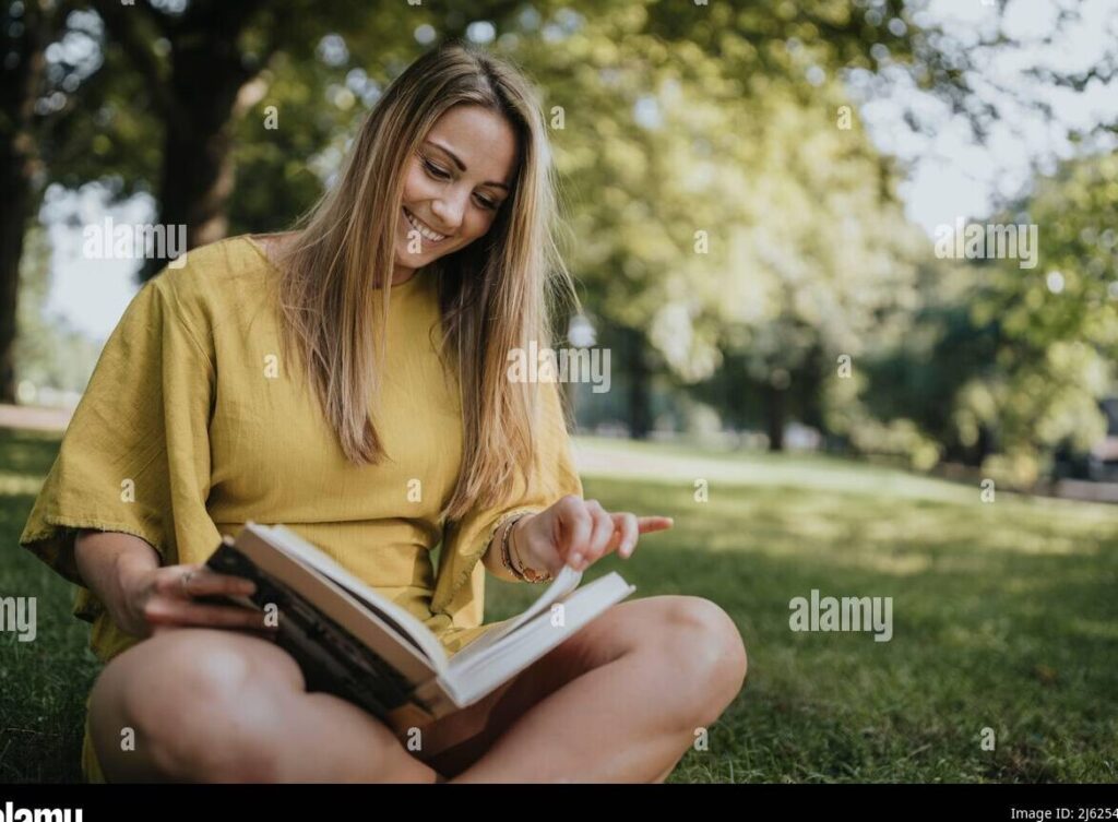 una nina sonriente leyendo un libro en un parque